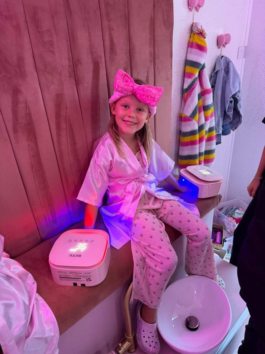 Smiling girl with a pink bow headband having her nails done