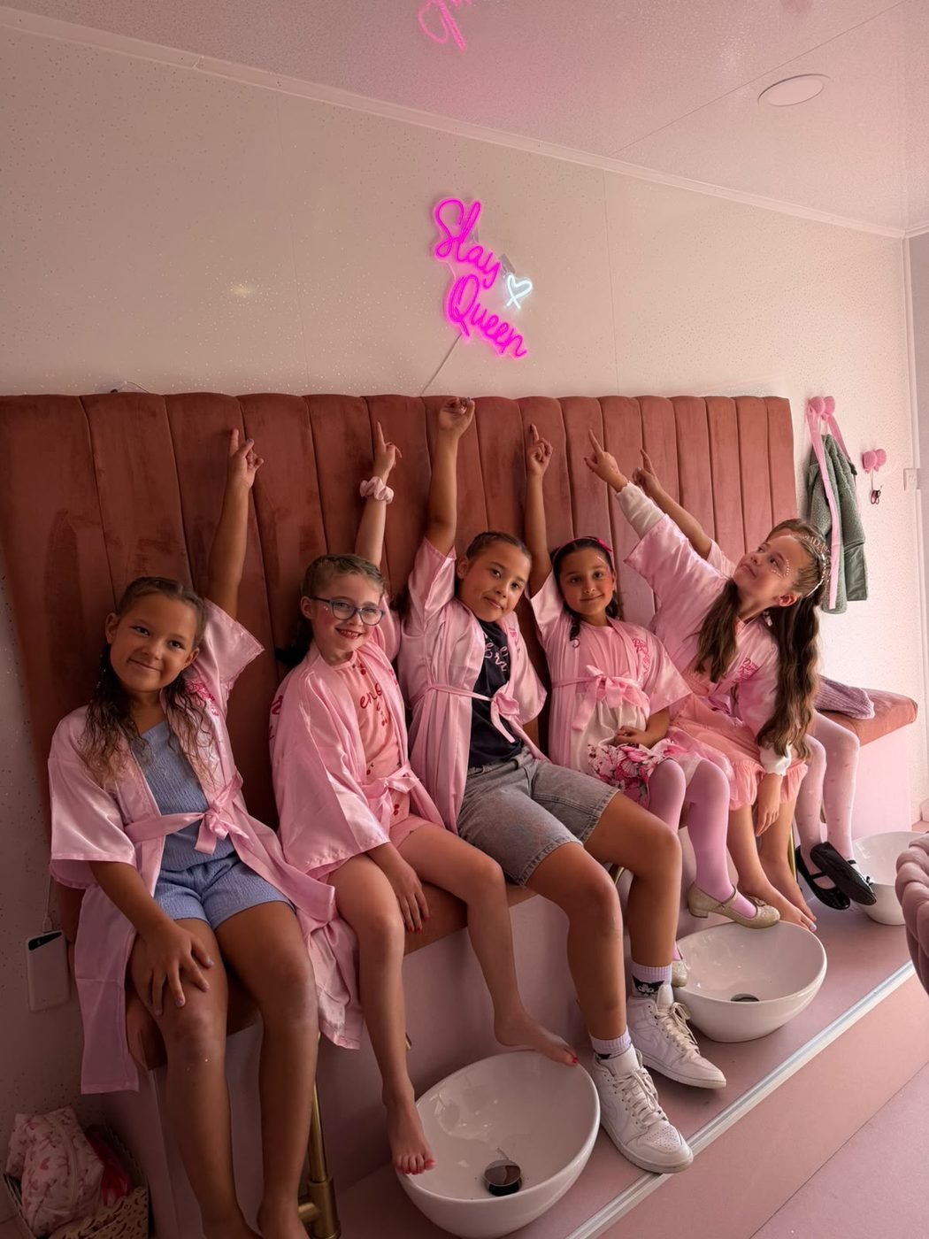 Group of princesses posing under the Slay Queen neon sign