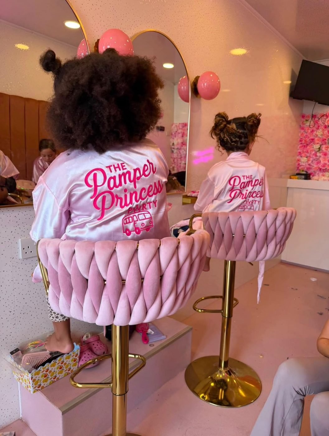 Princesses in Pamper Princess robes on pink velvet stools
