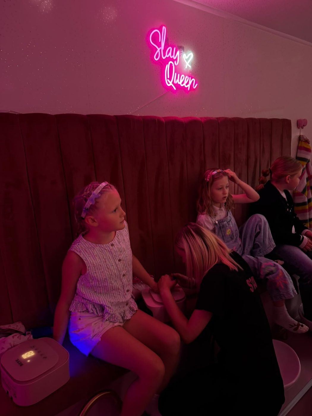 Mini manicures under the Slay Queen neon sign